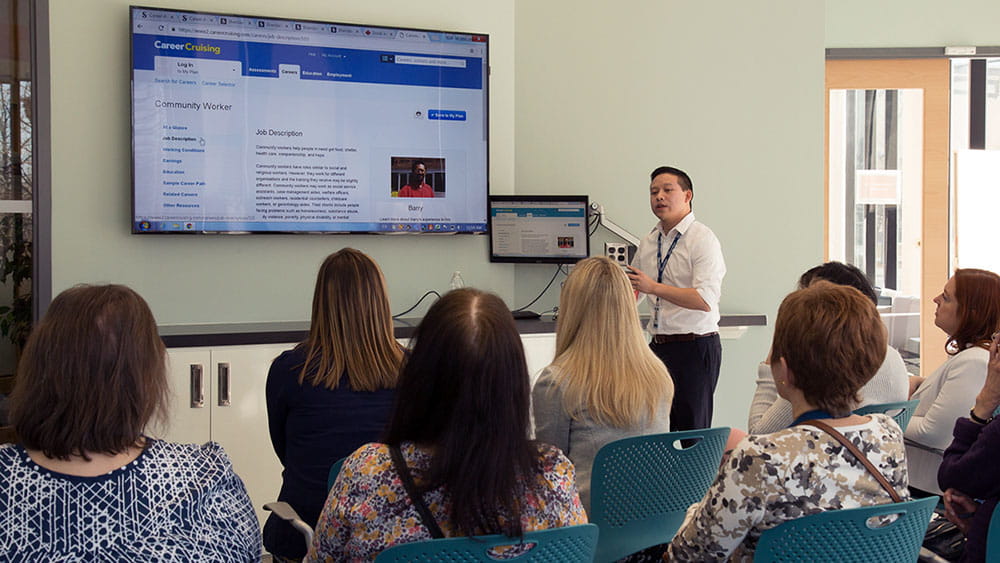 Sheridan representative standing next to a screen and presenting to a seated group.