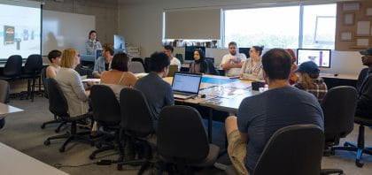 Students working around a table with one student presenting at the front