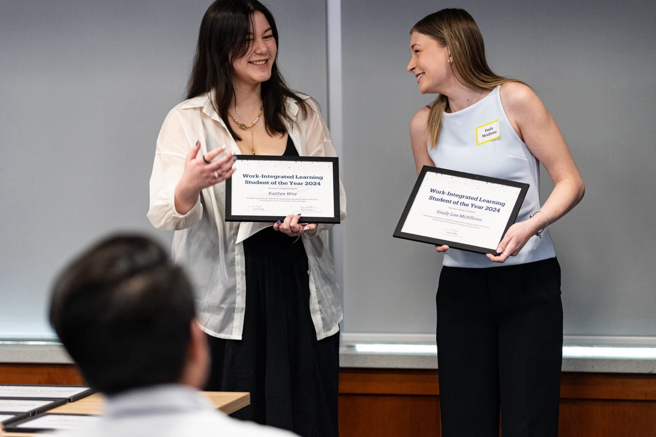 Award recipients Kaitlyn Way and Emily McAllister share a laugh while holding their certificates