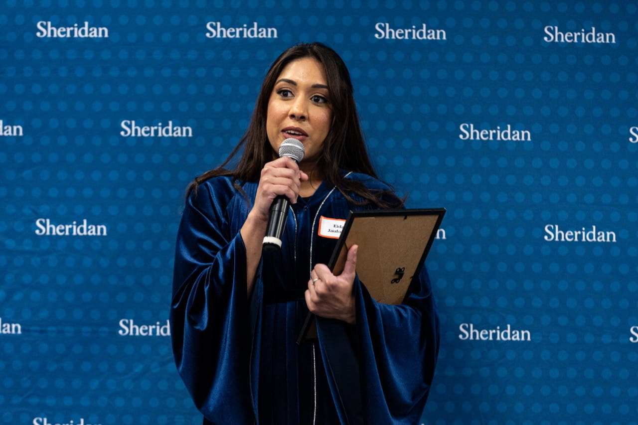 Eidah Jauforally delivers a speech while holding her framed certificate