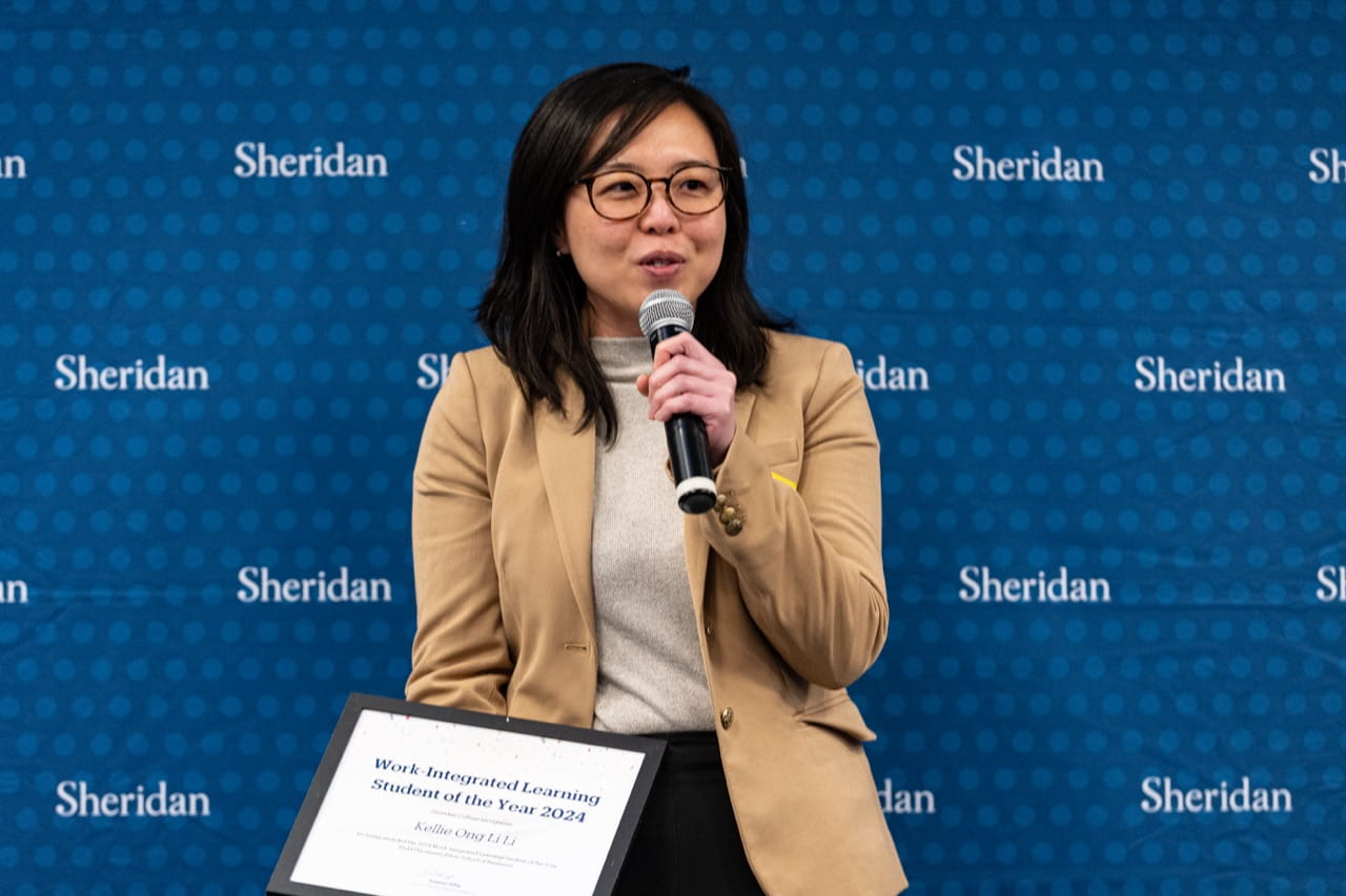 Kellie Ong Li Li delivers a speech while holding her framed certificate