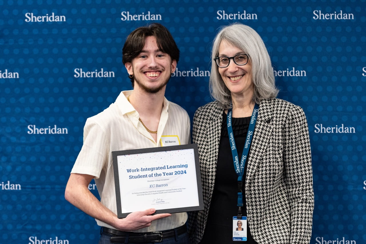 KC Barron holds his certificate while standing next to Sheridan Director, Clinical and Experiential Learning Lisa Sokoloff