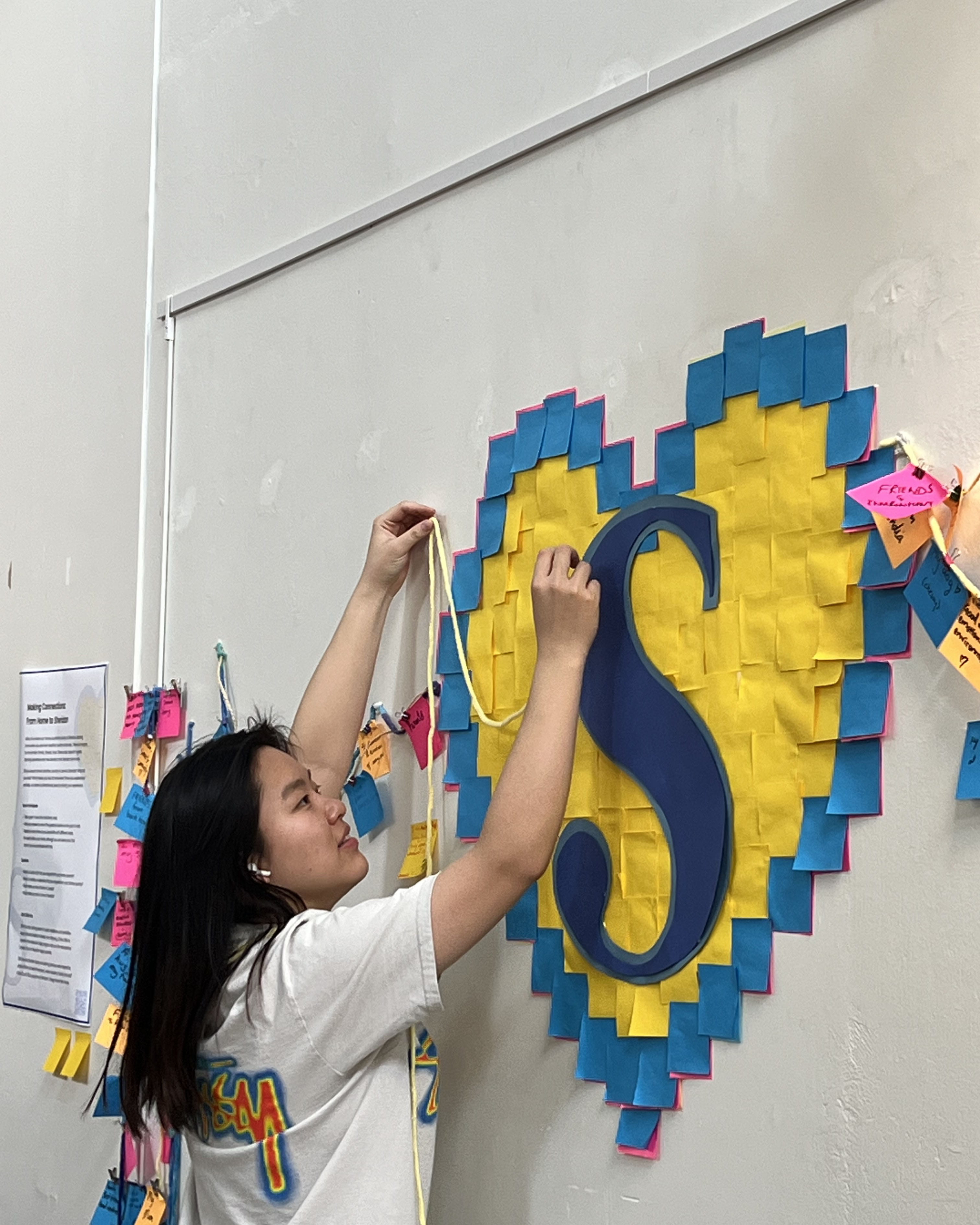 Zhilin Guo adds finishing touches to her interactive art display Making Connections: From Home to Sheridan