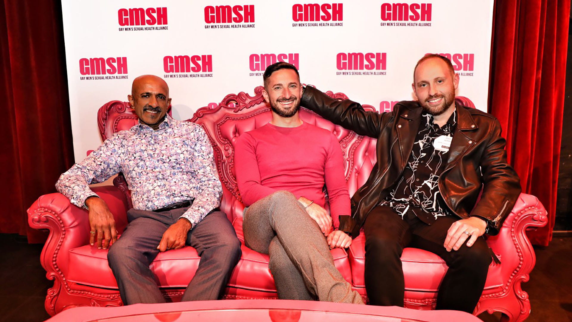 Three people sitting side-by-side on a sofa and smiling