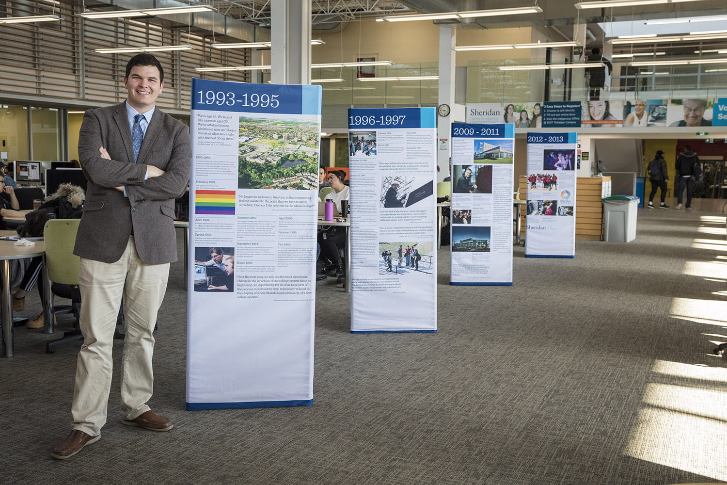 Peter Kikkert standing in front of panels he researched at Sheridan's Trafalgar Library