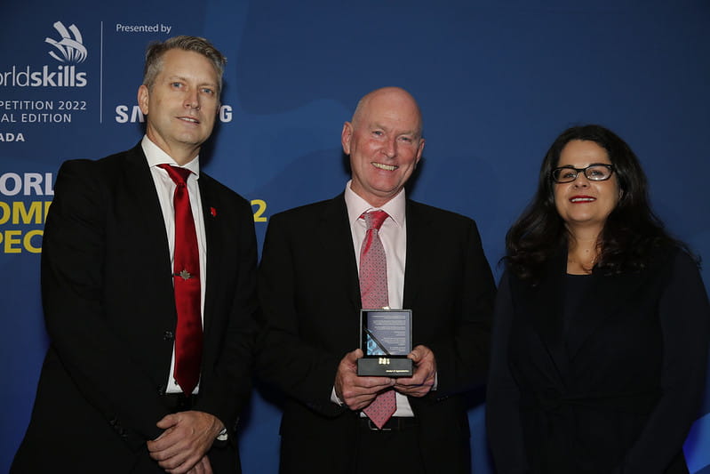 Sheridan millwrighting professor and WorldSkills Industrial Mechanics competition manager Craig Brazil displays a medal of appreciation he received from WorldSkills, standing between two Skills Canada officials.