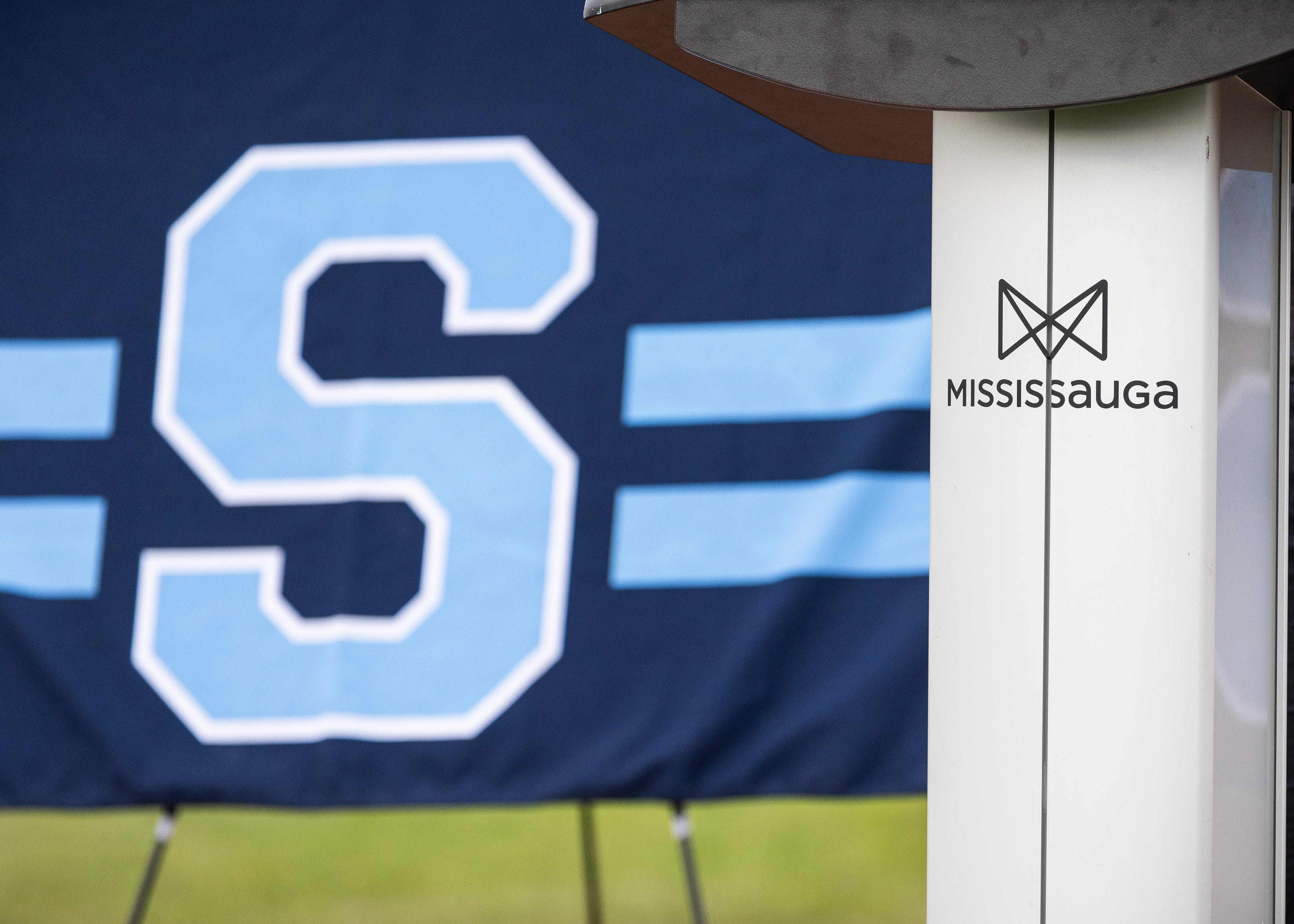 Sheridan Athletics 'S' flag in the background, with a close up of a podium featuring the City of Mississauga Logo