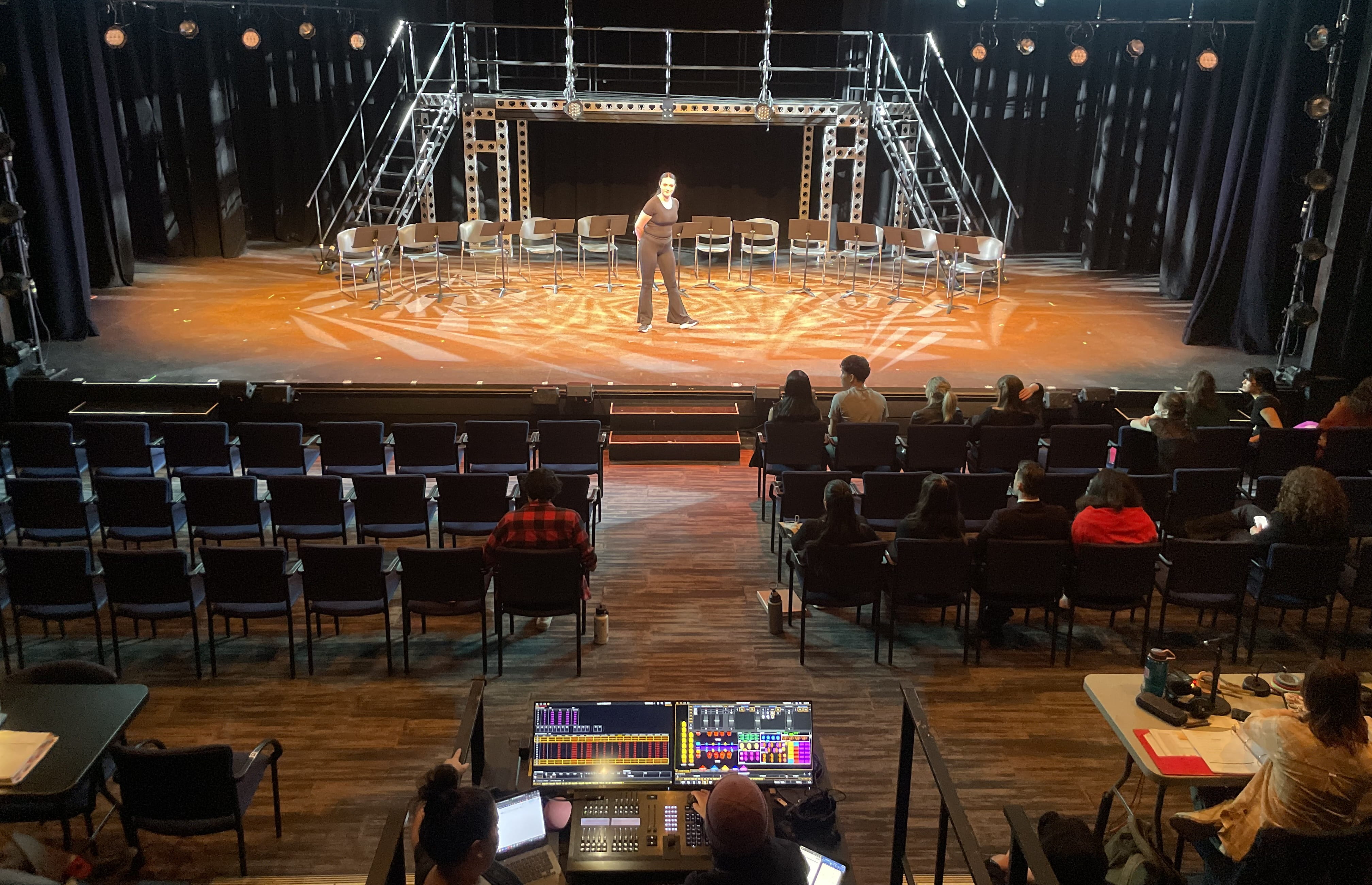 A performer takes centre stage while classmates sit in the audience seats to watch