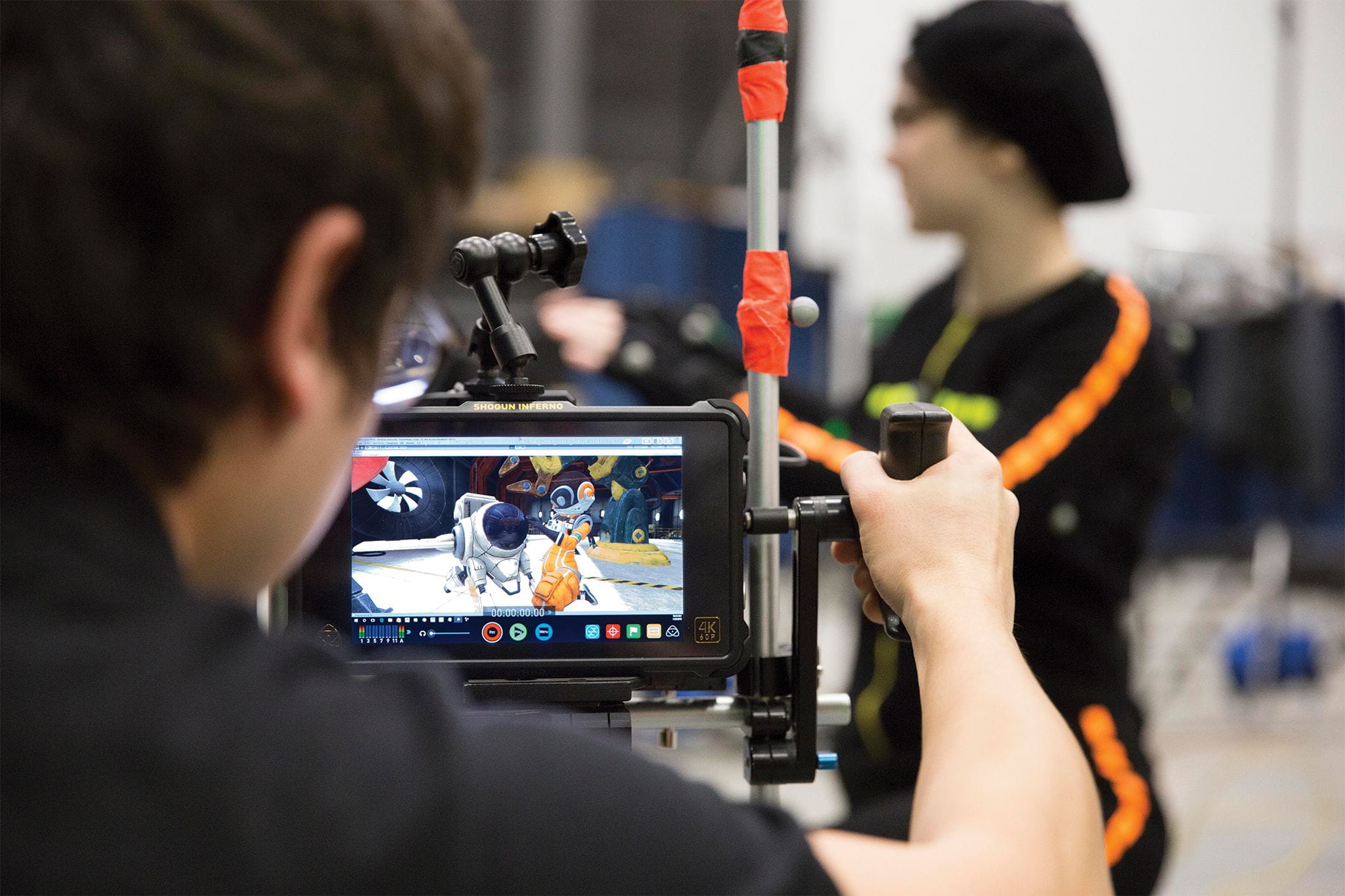 A camera person looks at their screen that depicts an animated scene