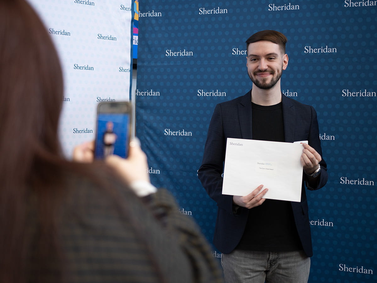 Student posing for a photo with an academic award in hand